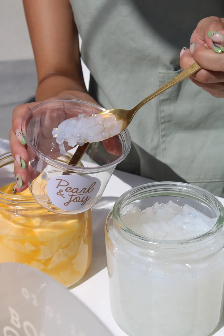 Pearl & Joy server adding lychee jelly to a branded boba cup