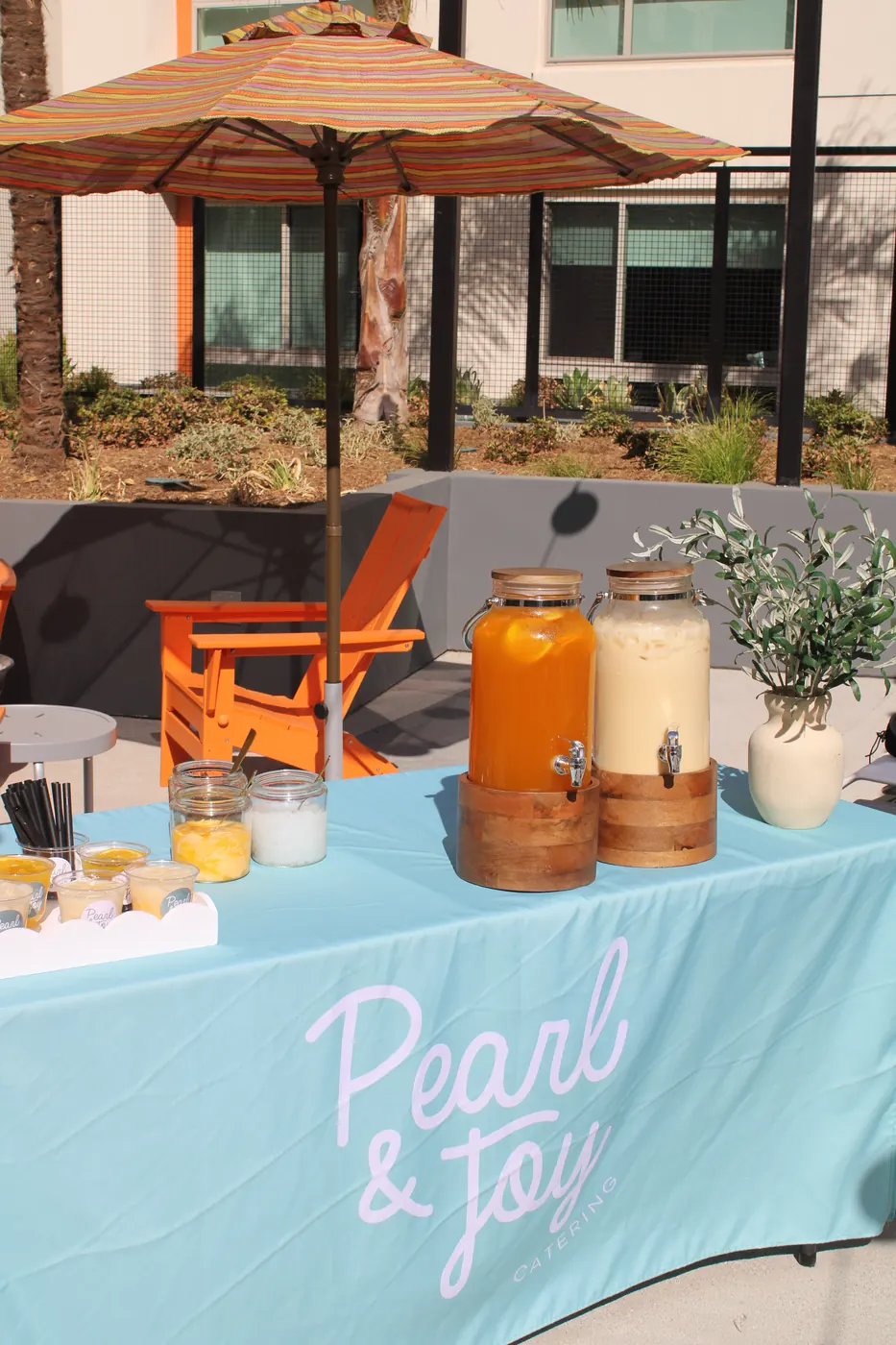 Pearl & Joy outdoor boba catering table beneath a colorful patio umbrella